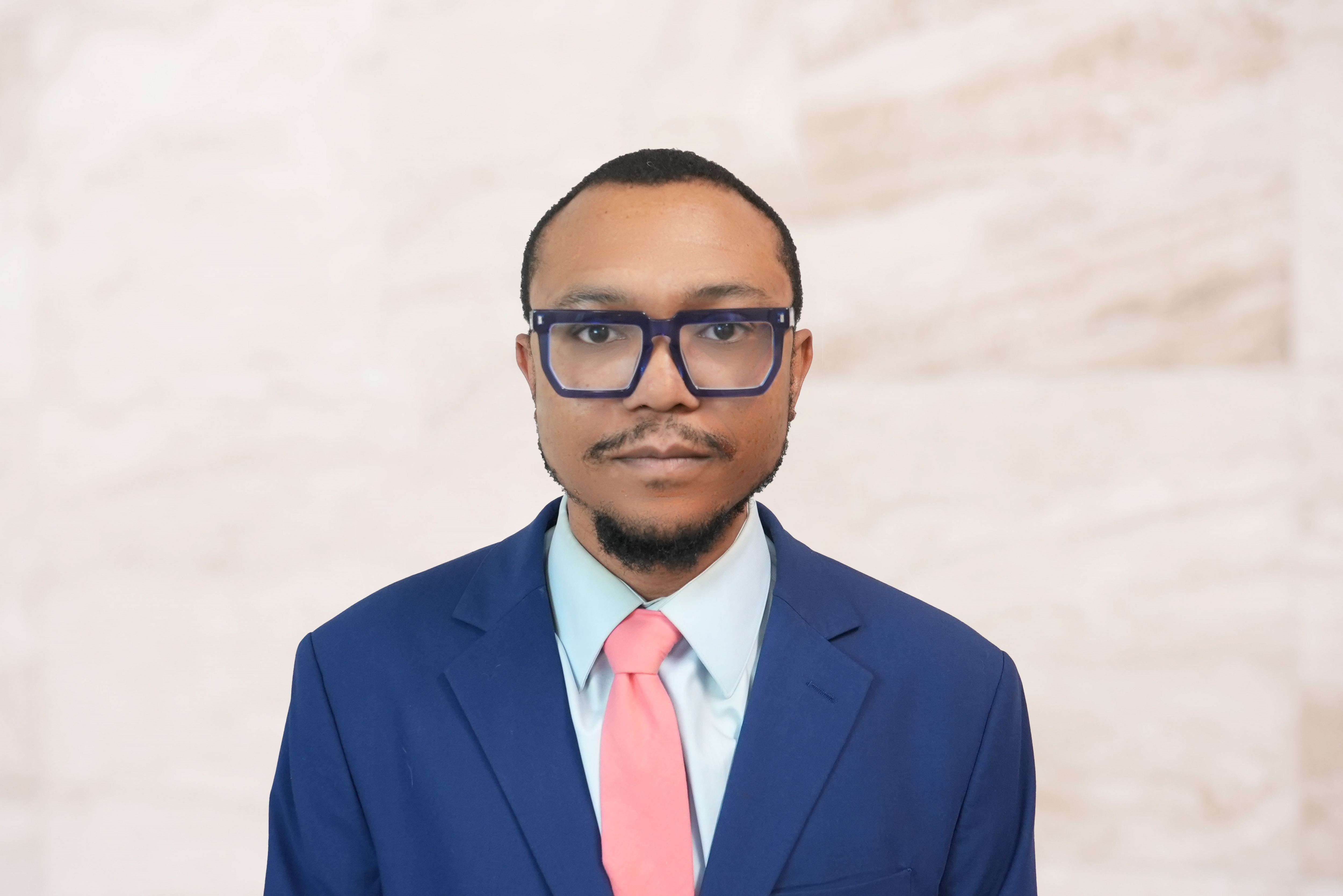 Solomon Holness, probate attorney, wearing a blue suit and pink tie, professional headshot against a neutral background, representing trust and expertise in legal matters.